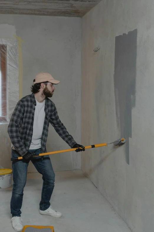 a man holding a pole in a room, pour paint, grey, background image, using a spade