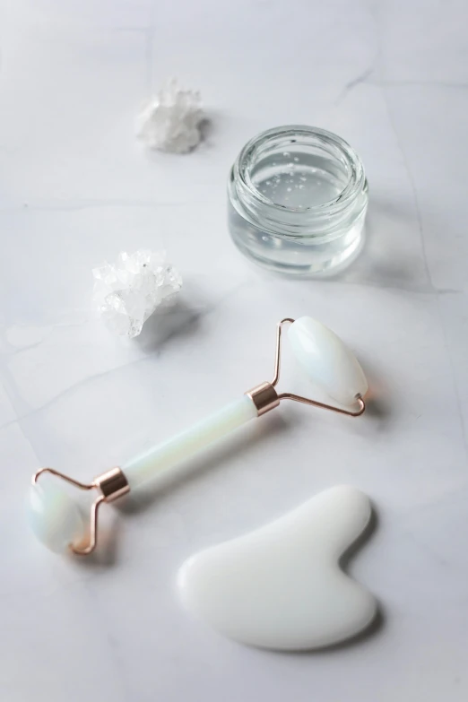 a couple of facial rollers sitting on top of a table, by Julia Pishtar, trending on pexels, white pearlescent, spoon, mint, glass arms