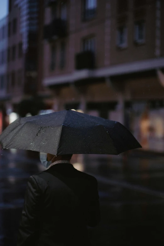 a person walking in the rain with an umbrella, a man wearing a black jacket, profile image, ignant, standing in a city street