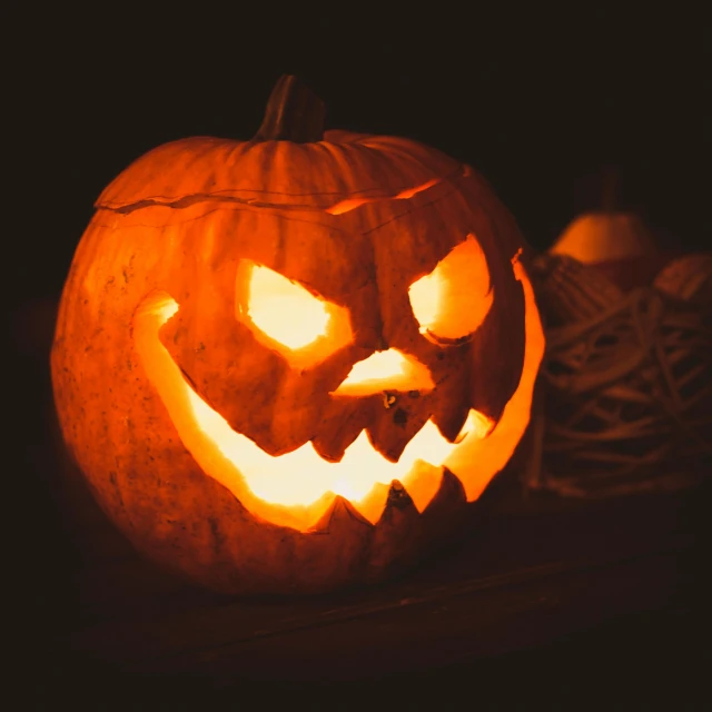 a carved pumpkin sitting on top of a table, an album cover, pexels, haunted expression, dark. no text, item, print ready