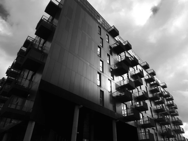 a black and white photo of a tall building, a black and white photo, unsplash, brutalism, crenellated balconies, moody sky, ten flats, monochrome!!!!!