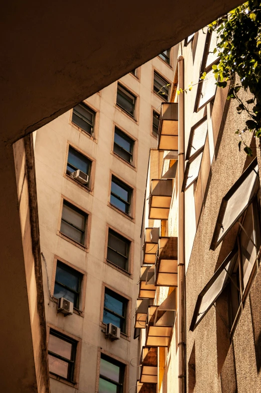 a tall building sitting next to a tall building, inspired by Ricardo Bofill, unsplash contest winner, cubism, late afternoon light, shady alleys, buenos aires, flying buttresses