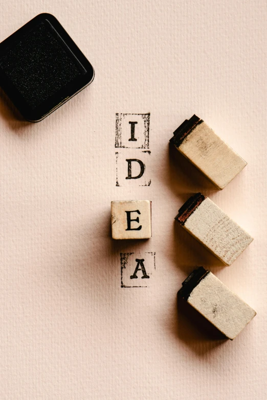 a couple of wooden blocks sitting on top of a table, poster art, trending on pexels, light bulb, rubber stamp, inspirational, unknown artist