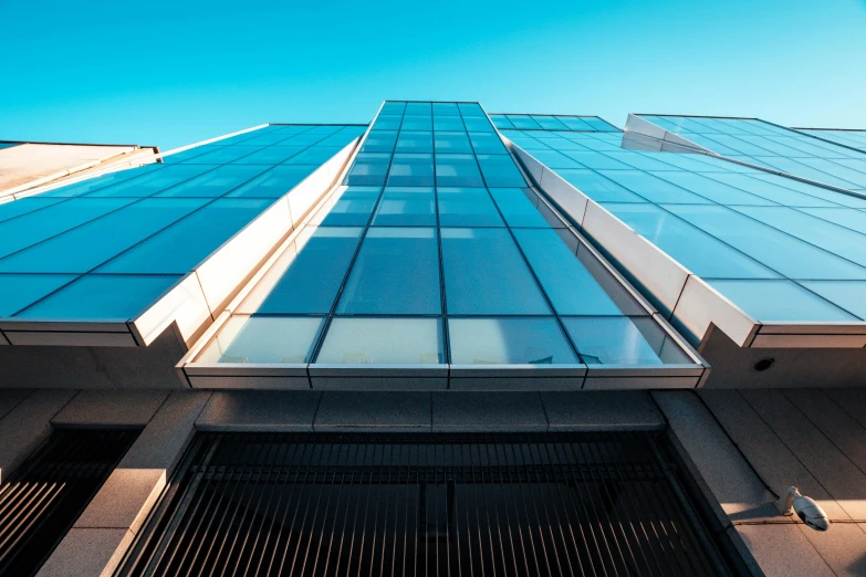 a tall building with a blue sky in the background, by David Donaldson, unsplash, glass openings, tall entry, clear sky above, thumbnail