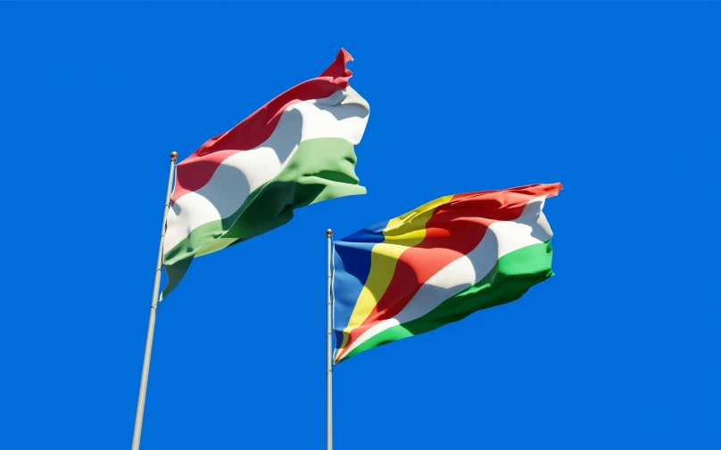 two flags blowing in the wind against a blue sky, a digital rendering, inspired by Károly Patkó, shutterstock, hurufiyya, multi colored, larapi, van lieven, 3 colours