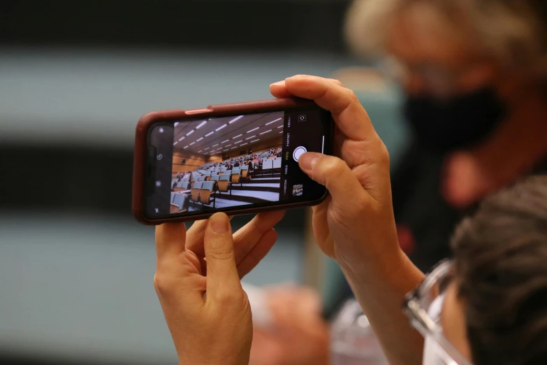 a person taking a picture with a cell phone, by Matthias Stom, happening, un meeting at the hague, zoomed in, covid, thumbnail