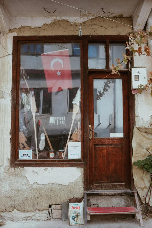 a wooden door sitting in front of a window, inspired by Géza Mészöly, flags, shop front, turkey, vintage vibe