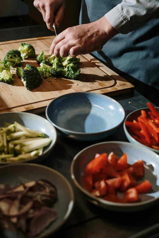 a person chopping vegetables on a cutting board, bowl filled with food, broccoli, pièce de résistance, plating