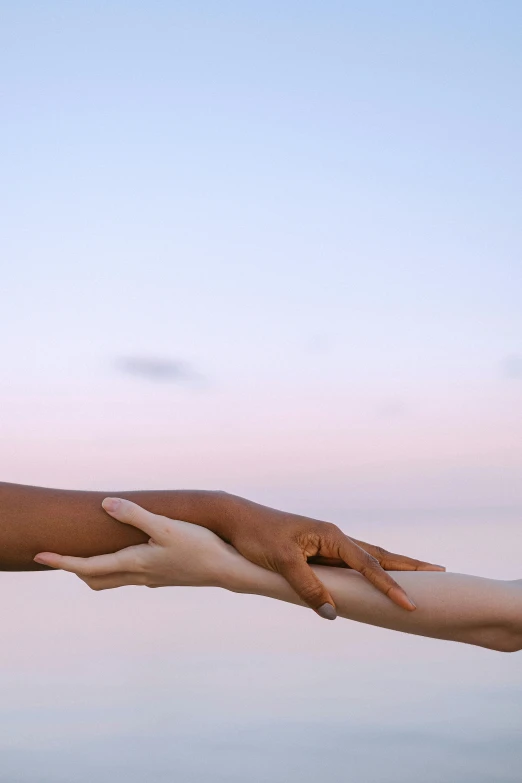 a man and a woman holding hands over a body of water, bright sky, varying ethnicities, closeup of arms, dawn