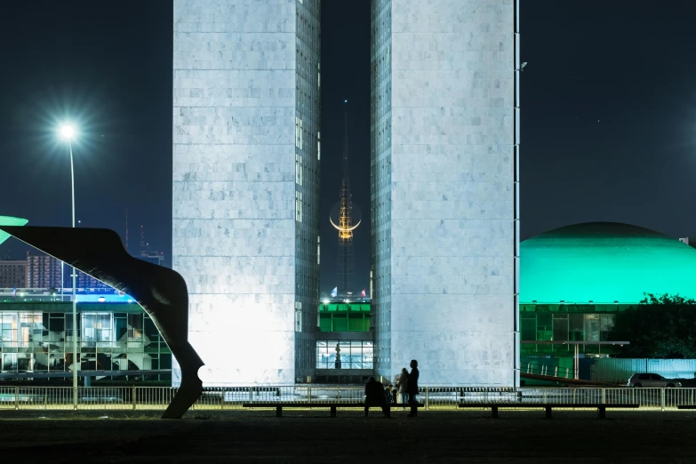 a couple of people standing in front of a tall building, a statue, inspired by Nil Gleyen, pexels contest winner, brutalism, nighttime foreground, cybermosque interior, electricity archs, maintenance photo