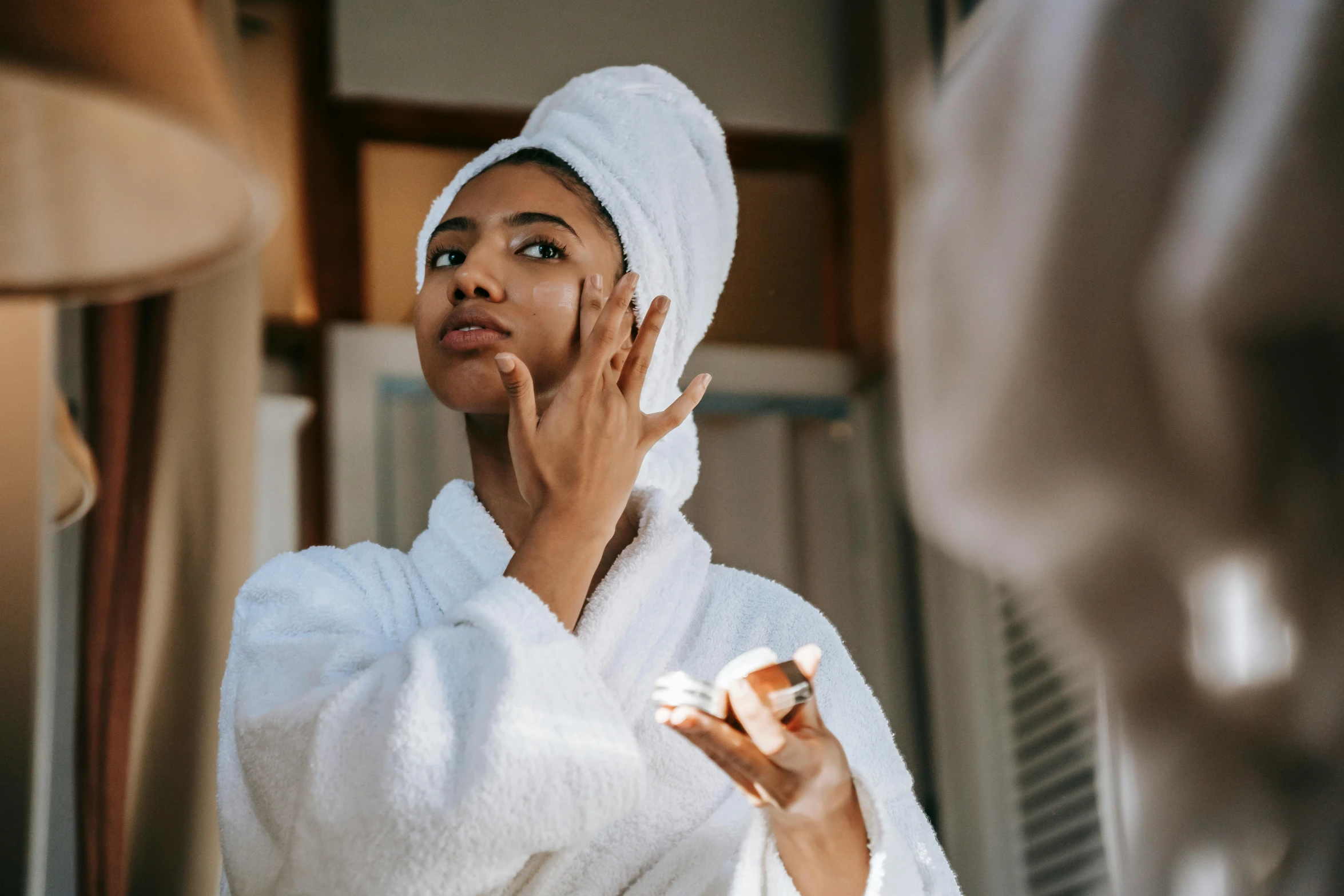 a woman standing in front of a mirror with a towel on her head, trending on pexels, renaissance, wearing a white robe, manuka, with brown skin, manicured