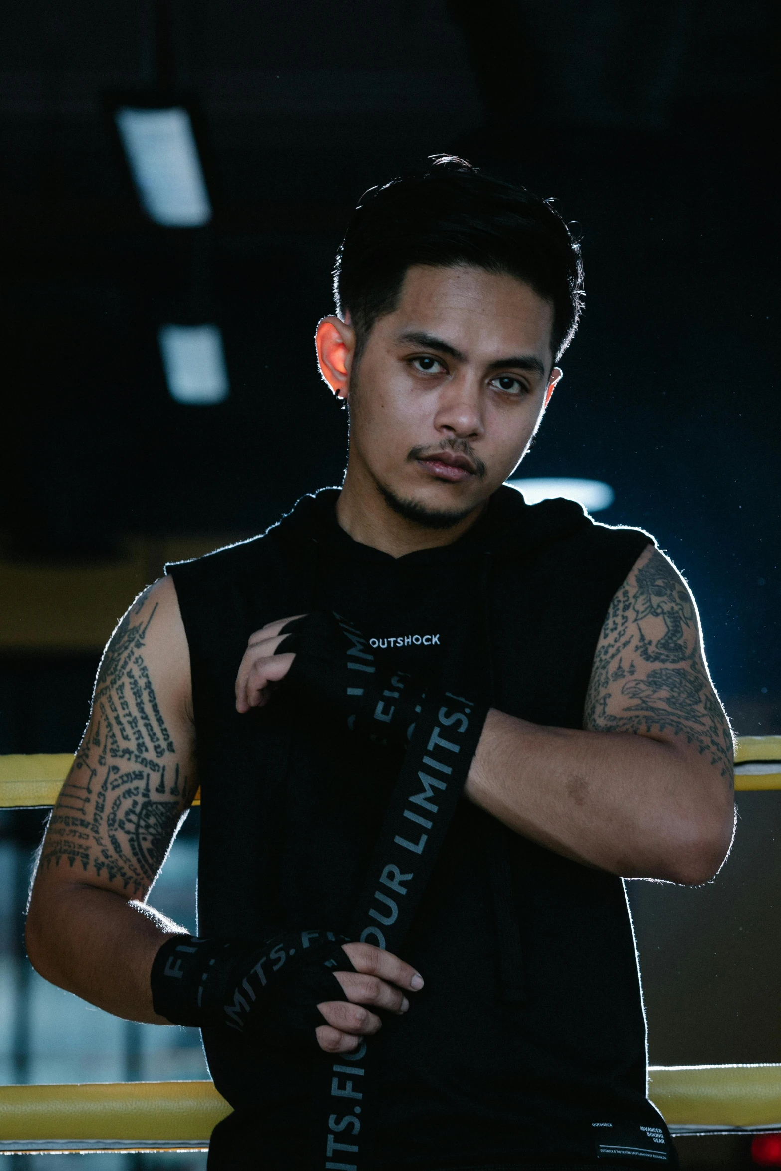 a man with tattoos standing in a boxing ring, inspired by Eddie Mendoza, pexels contest winner, black swat vest, malaysian, plain background, lookbook