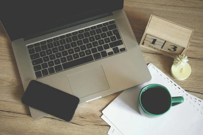 a laptop computer sitting on top of a wooden desk, by Carey Morris, trending on unsplash, black and green scheme, coffee, 9 9 designs, miscellaneous objects