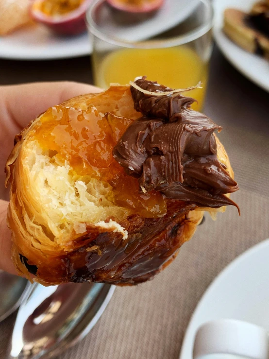 a close up of a person holding a pastry, by Robbie Trevino, some chocolate sauce, seville, panorama, orange