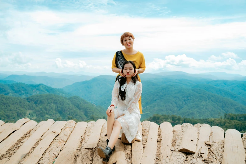 a man and a woman sitting on top of a wooden roof, by Tan Ting-pho, pexels contest winner, mountainous background, sisters, ulzzang, white