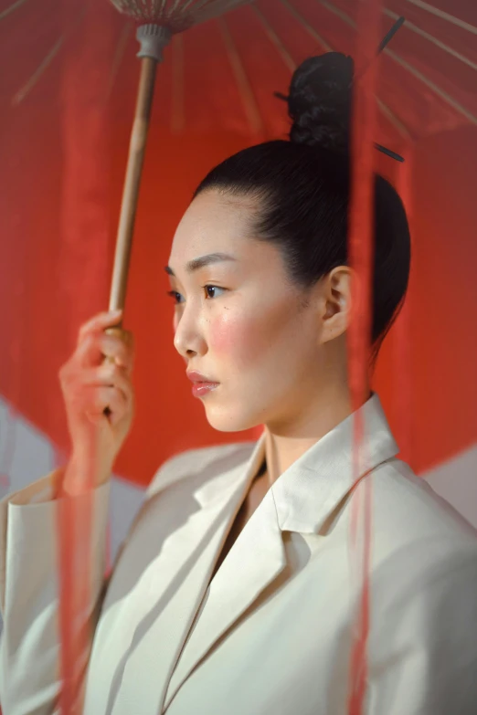 a woman in a white suit holding a red umbrella, inspired by Itō Shinsui, unsplash, lucy liu portrait, hito steyerl, demur, ( ( theatrical ) )