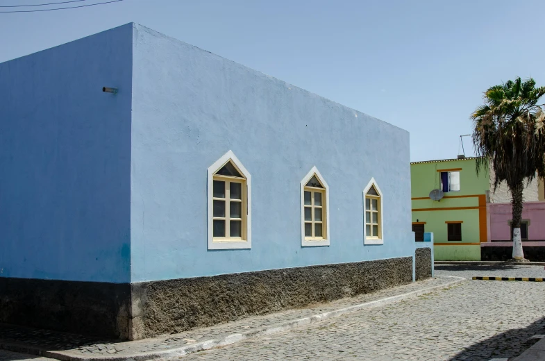 a blue building sitting on the side of a road, inspired by Ceferí Olivé, square, afar, preserved historical, grey