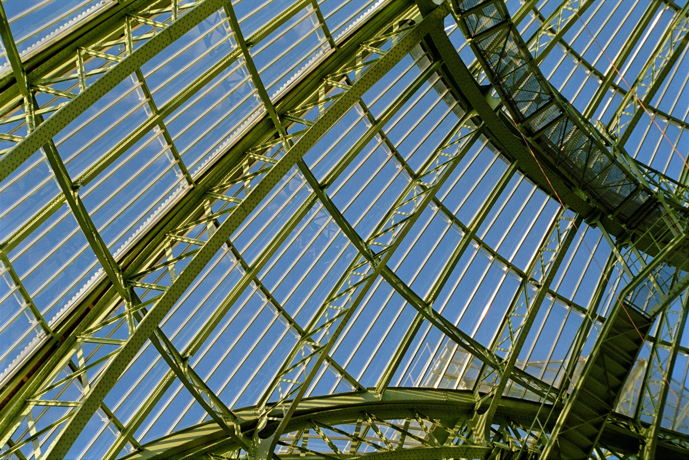 a clock hanging from the ceiling of a building, by Jan Rustem, pixabay, art nouveau, huge greenhouse, green and blue colour palette, viewed from below, detail structure