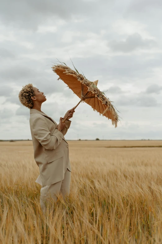 a man standing in a field holding an umbrella, short blonde afro, in a wheat field, profile image, trending photo