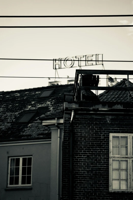a black and white photo of a hotel sign on top of a building, inspired by Elsa Bleda, happening, in legnica!!!, exposed wires, creepy mood, rooftop party