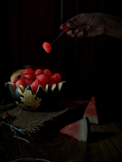 a person dipping a piece of watermelon into a bowl, by Adam Marczyński, dark. studio lighting, berries inside structure, halloween, profile image