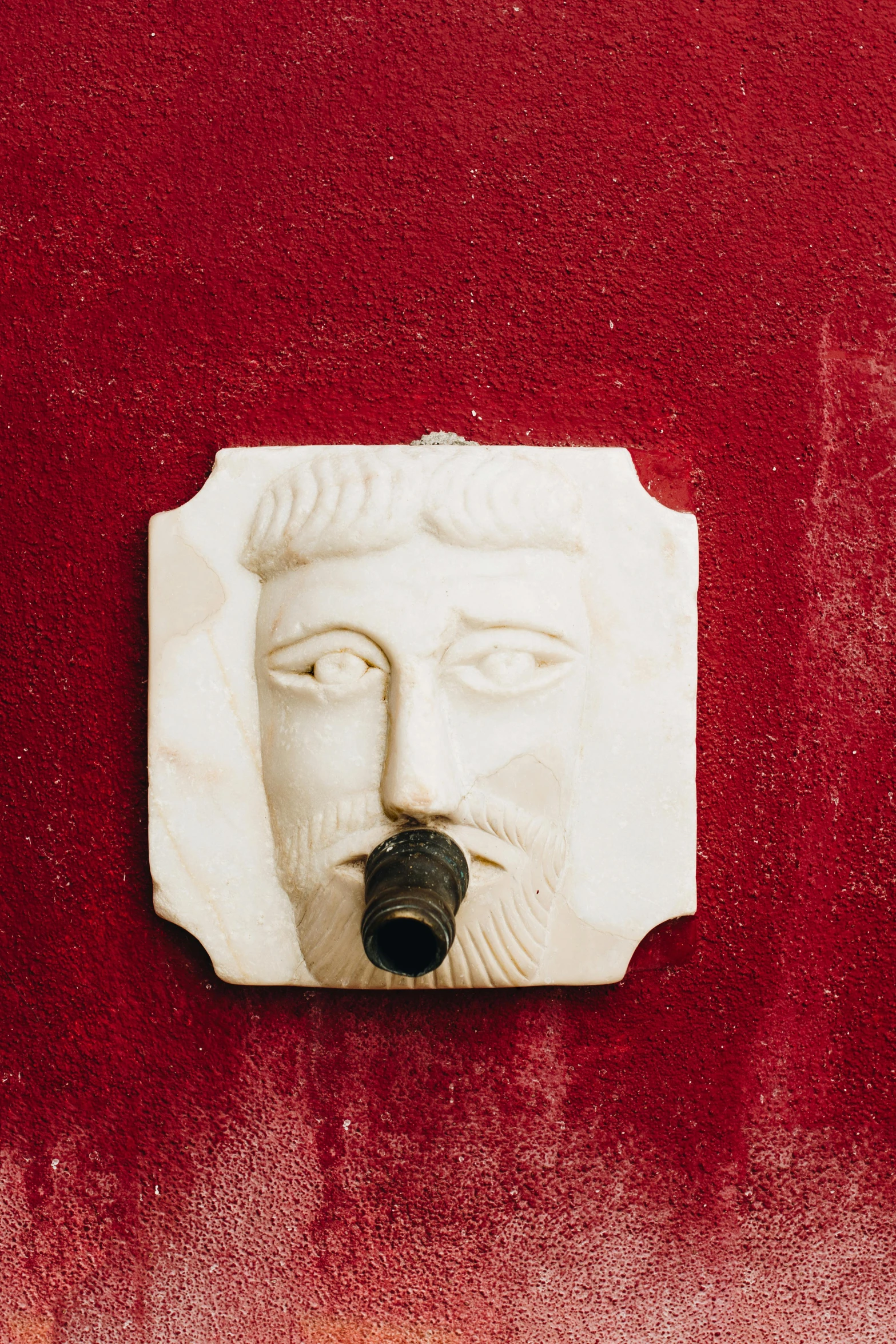 a close up of a plaque on a wall, a marble sculpture, inspired by Taddeo Gaddi, pexels contest winner, hooked nose and square jaw, red wall, water pipe, facial hair