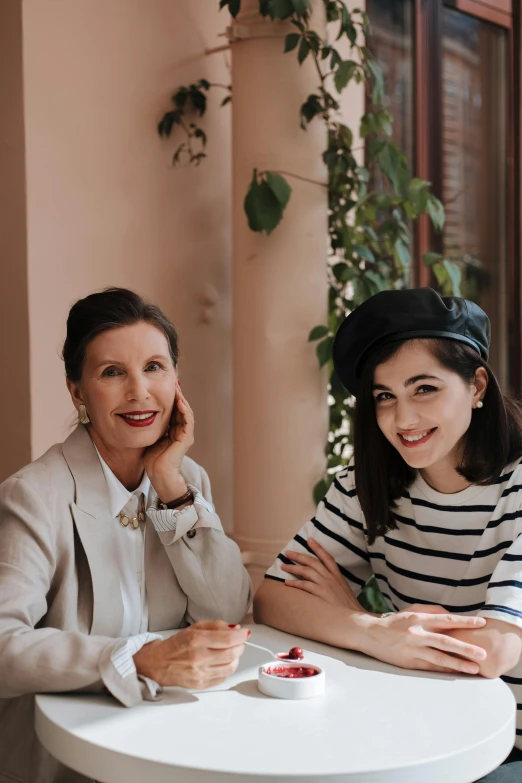 two women sitting at a table next to each other, a portrait, by Arabella Rankin, pexels contest winner, wearing a french beret, marie - gabrielle capet style, daughter, promo image