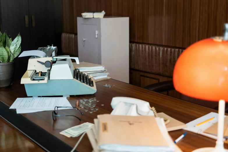 a typewriter sitting on top of a wooden desk, an album cover, by Elsa Bleda, unsplash, brutalist office buildings, orange lamp, 1 9 7 0 s photo, set inside of the bank