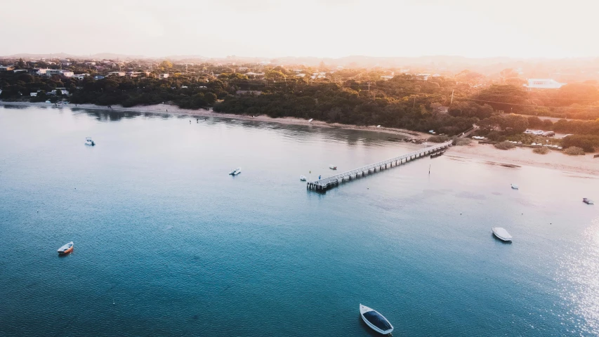 a group of boats floating on top of a body of water, by Lee Loughridge, pexels contest winner, near a jetty, australian beach, sunfaded, airplane view