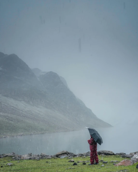 a person standing in a field with an umbrella, pexels contest winner, mountain water, cold colours, glacier, she's sad