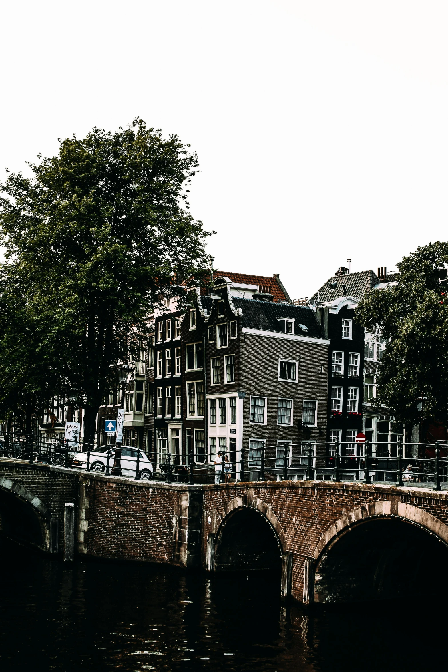 a bridge over a body of water with buildings in the background, a photo, by Jan Tengnagel, pexels contest winner, neoclassicism, dutch houses along a river, panoramic view of girl, background image, city buildings on top of trees