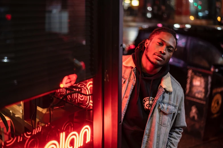 a man standing in front of a neon sign, a photo, trending on pexels, realism, handsome hip hop young black man, killian eng, taverns nighttime lifestyle, : kendrick lamar