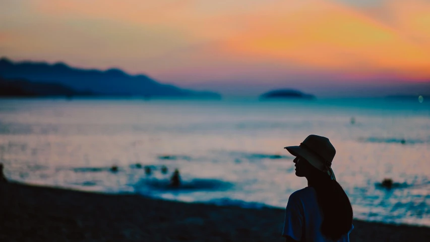 a man standing on top of a beach next to the ocean, pexels contest winner, romanticism, she is wearing a hat, beautiful dusk, profile image, a woman's profile