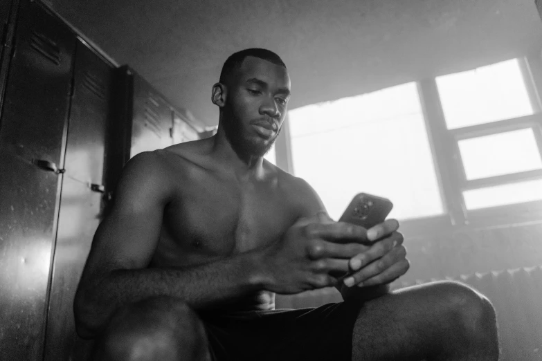 a black and white photo of a man holding a cell phone, wearing a low cut tanktop, jaylen brown, programming, 2019 trending photo