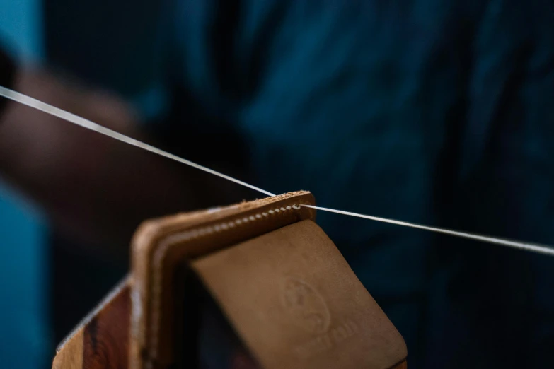 a close up of a person weaving a piece of wood, an album cover, trending on unsplash, arts and crafts movement, intricate leather suspenders, tonal topstitching, ignant, fyling silk