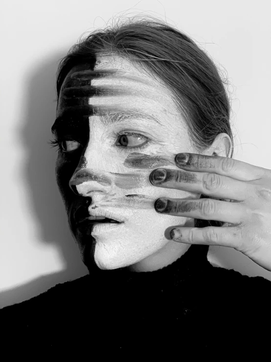 a black and white photo of a woman covering her face with her hands, a black and white photo, by Lucia Peka, hyperrealism, facepaint facepaint facepaint, half and half, multiple faces, prosthetic makeup