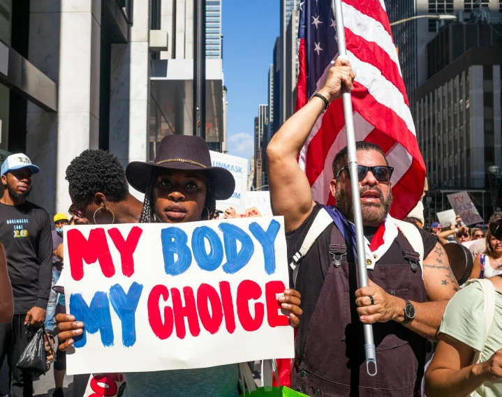 a man holding a sign that says my body is my choice, a photo, pexels contest winner, renaissance, patriotic, big crowd, essence, organ harvesting