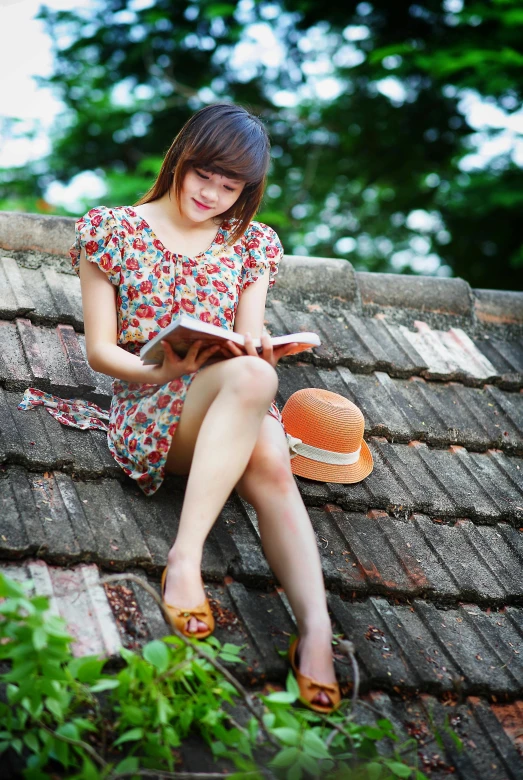 a woman sitting on a roof reading a book, wearing a cute hat, wearing orange sundress, in style of lam manh, girl with brown hair