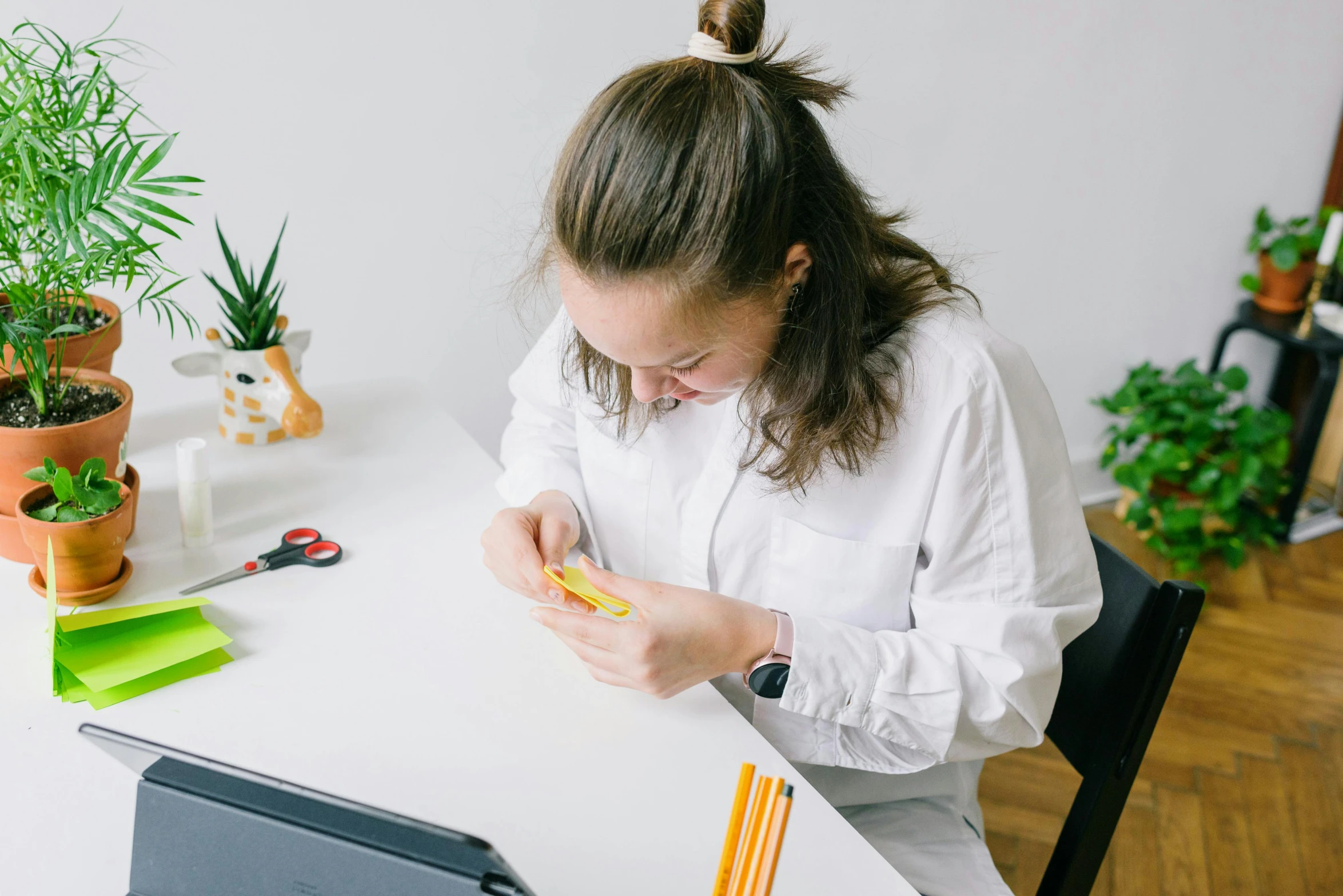 a woman sitting at a table in front of a laptop, by Nicolette Macnamara, pexels contest winner, academic art, holding a yellow toothbrush, teen girl, bend over posture, she is holding a smartphone