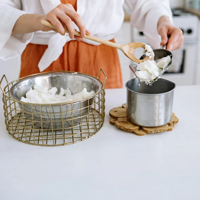 a woman in an orange apron cooking marshmallows, a still life, inspired by Yukimasa Ida, pexels, white metal, gif, whipped cream, product introduction photo