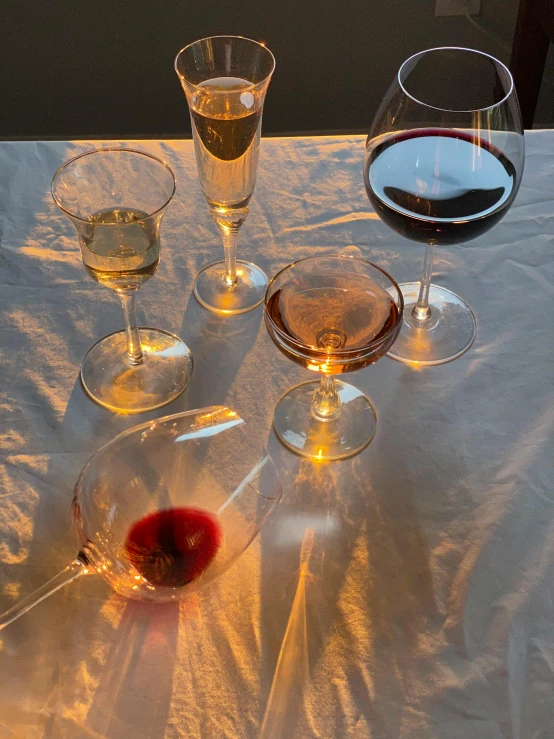 a group of wine glasses sitting on top of a table, a still life, pexels contest winner, taken on iphone 1 3 pro, evening sun, on a velvet table cloth, high resolution product photo