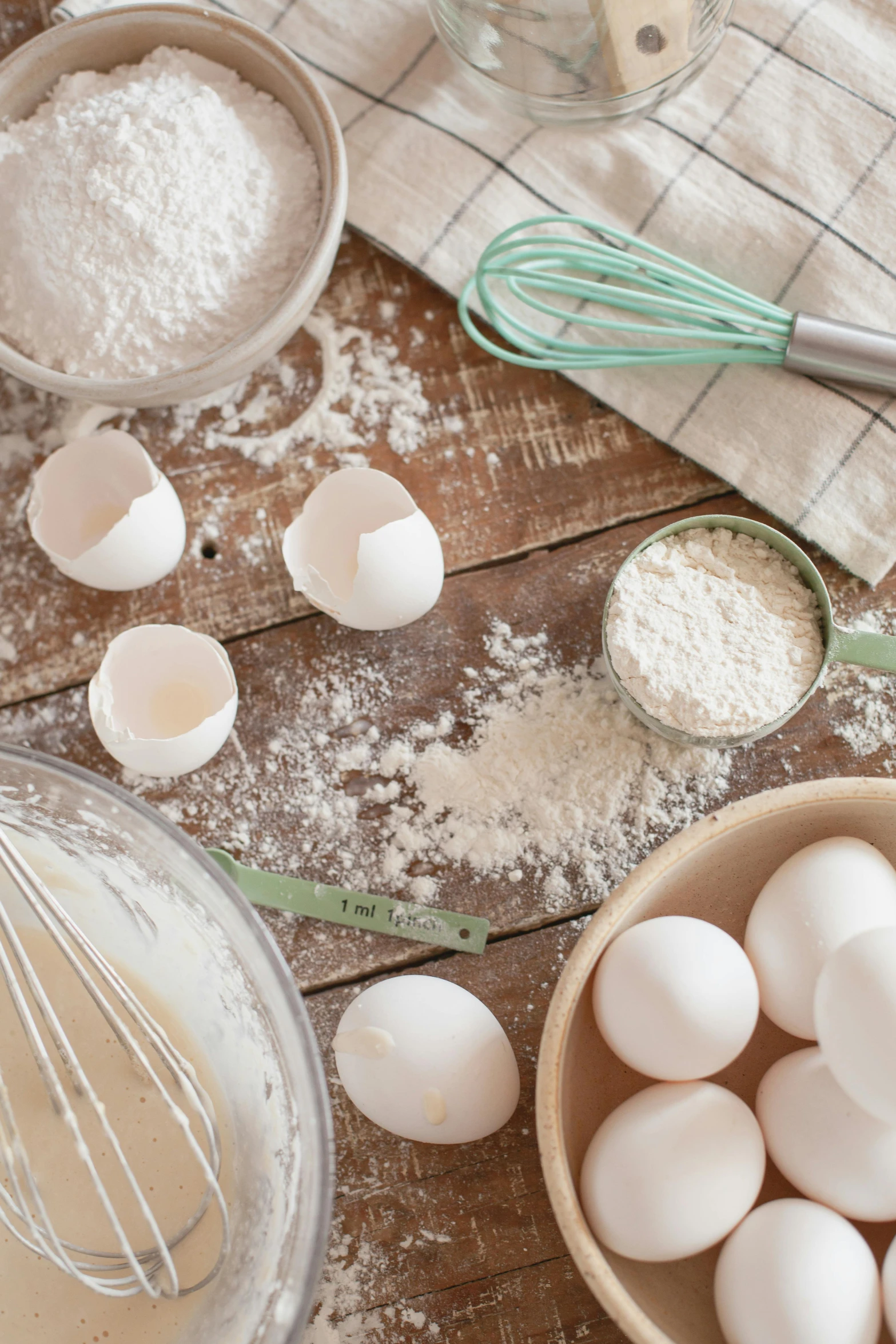 a wooden table topped with bowls of eggs and a whisk, trending on pexels, process art, flour dust, square, banner, mint