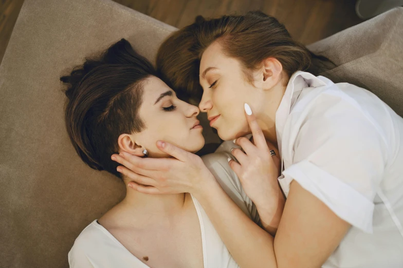 a couple of women laying on top of a couch, by Emma Andijewska, trending on pexels, romanticism, androgynous face, lesbian kiss, close face view, 15081959 21121991 01012000 4k