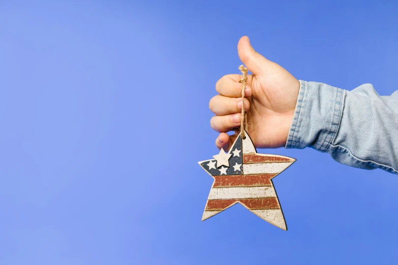 a person's hand holding a wooden star ornament, pexels contest winner, uncle sam, avatar image, background image, profile picture