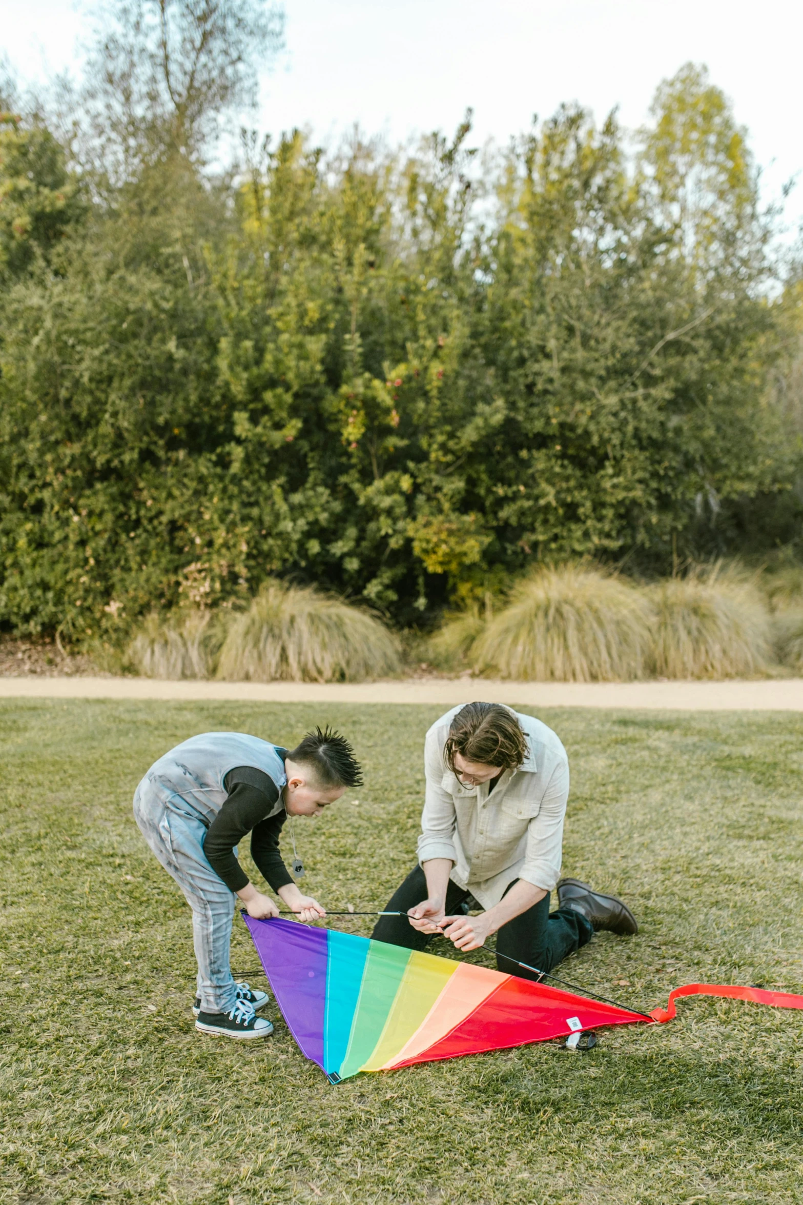 a couple of people that are in the grass with a kite, sydney park, pride month, gardening, preparing to fight