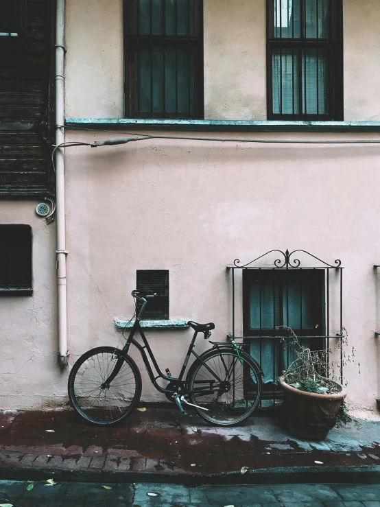 a bicycle parked in front of a pink building, inspired by Elsa Bleda, pexels contest winner, black and terracotta, profile image, dirty and old, photography]