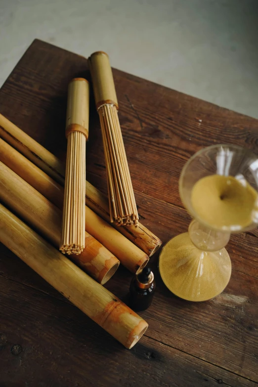 a bunch of bamboo sticks sitting on top of a wooden table, inspired by Kanō Shōsenin, renaissance, bottles covered in wax, yellow ochre, products shot, cigar