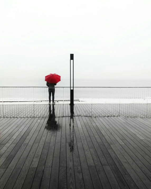 a person with a red umbrella standing on a pier, all alone, looking off into the distance, instagram post, dreary