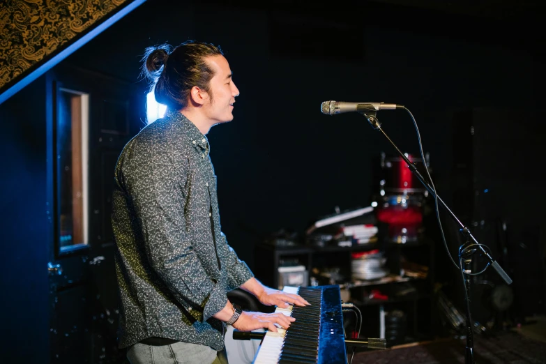 a man playing a piano in front of a microphone, happening, jonny wan, looking to the side off camera, the backrooms, gemma chen