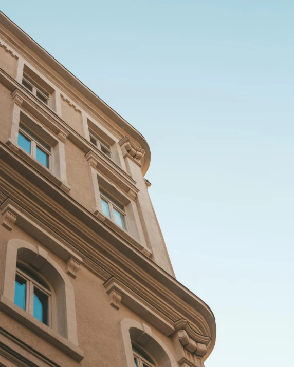 a tall building with a clock on it's side, pexels contest winner, neoclassicism, cyan shutters on windows, sand - colored walls, view from below, young handsome pale roma